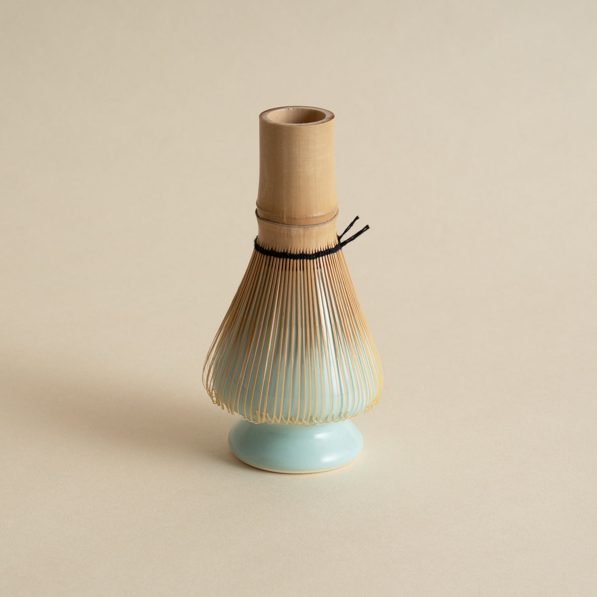 Tea whisk with a ceramic holder on a beige background