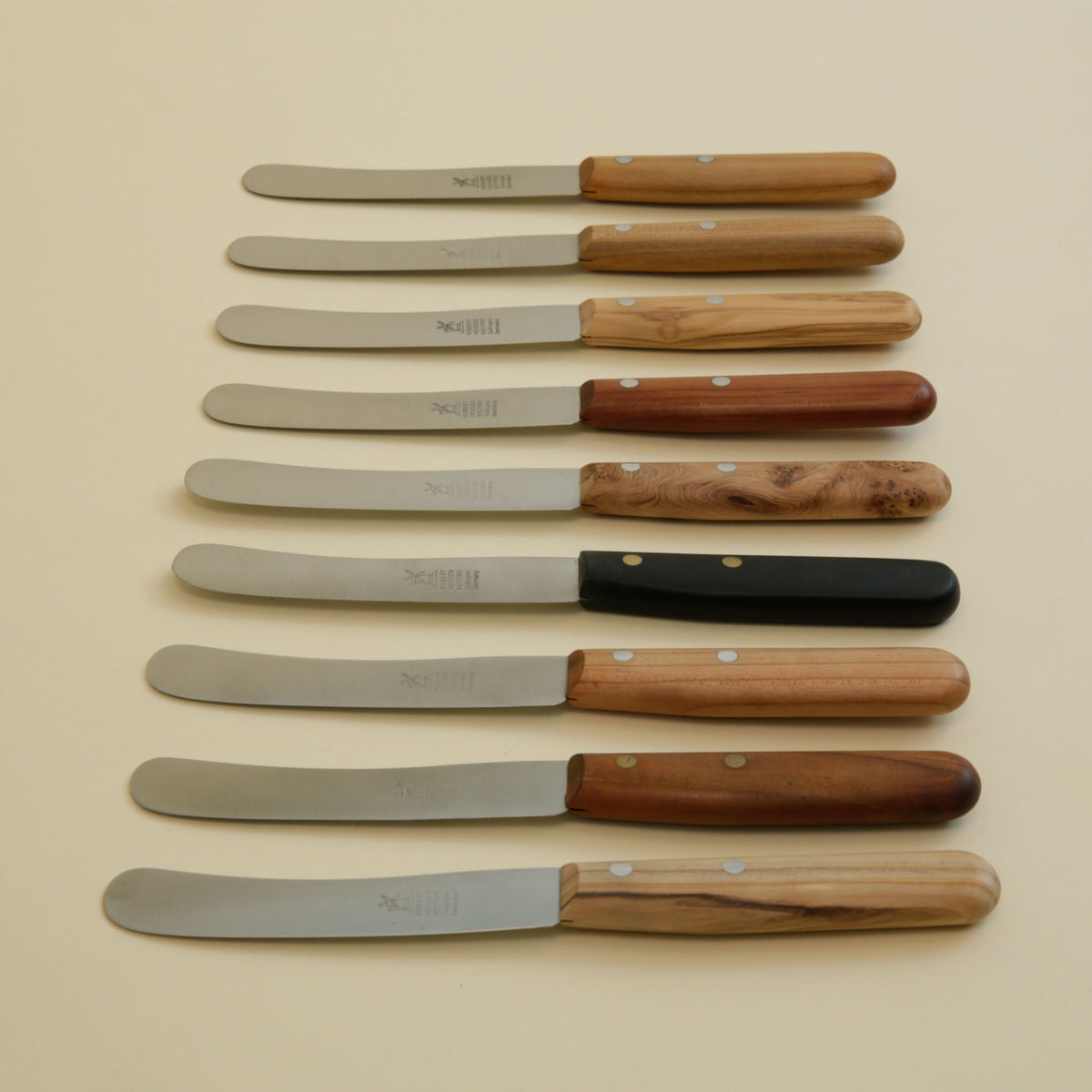 Old German all-purpose knives lined up showing nine handle options in POM and natural woods