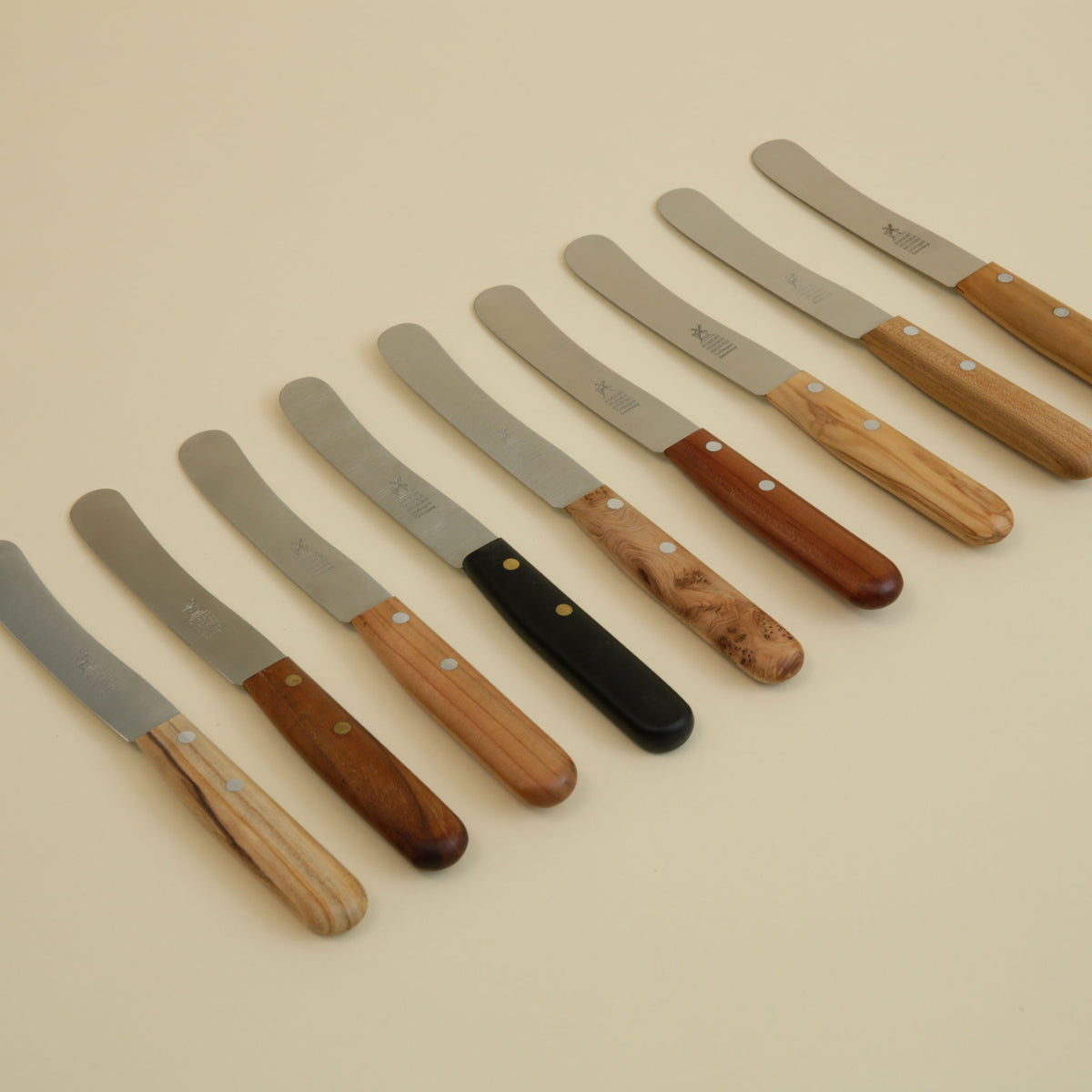 Old German all-purpose knives lined up showing nine handle options in POM and natural woods