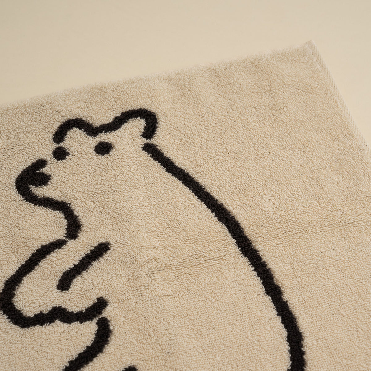 Warmgrey Tail terry face towel with a line-drawn illustration of a standing bear on a cream ground