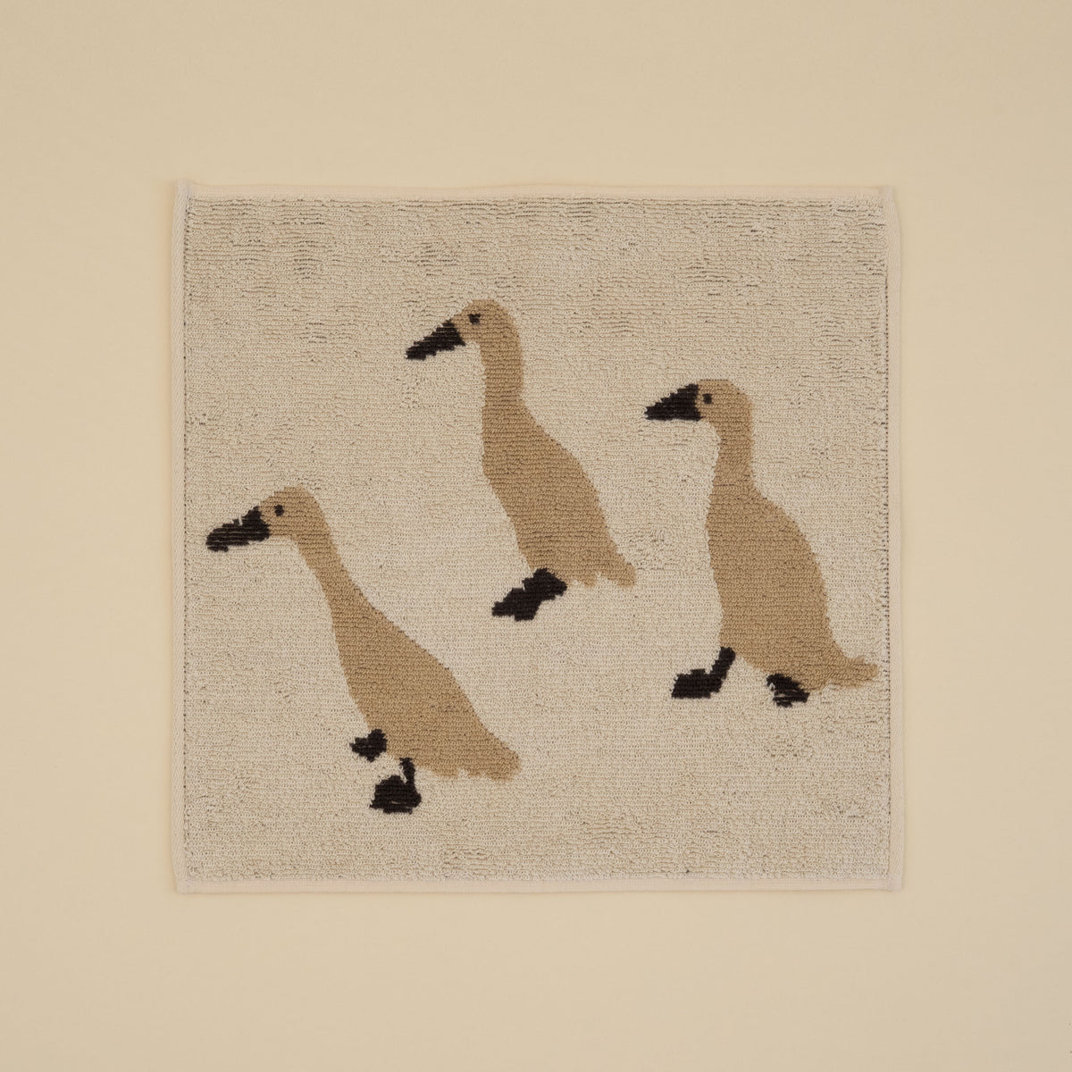 Warmgrey Tail terry face towel with an illustration of three Indian Runner ducks on an ivory ground