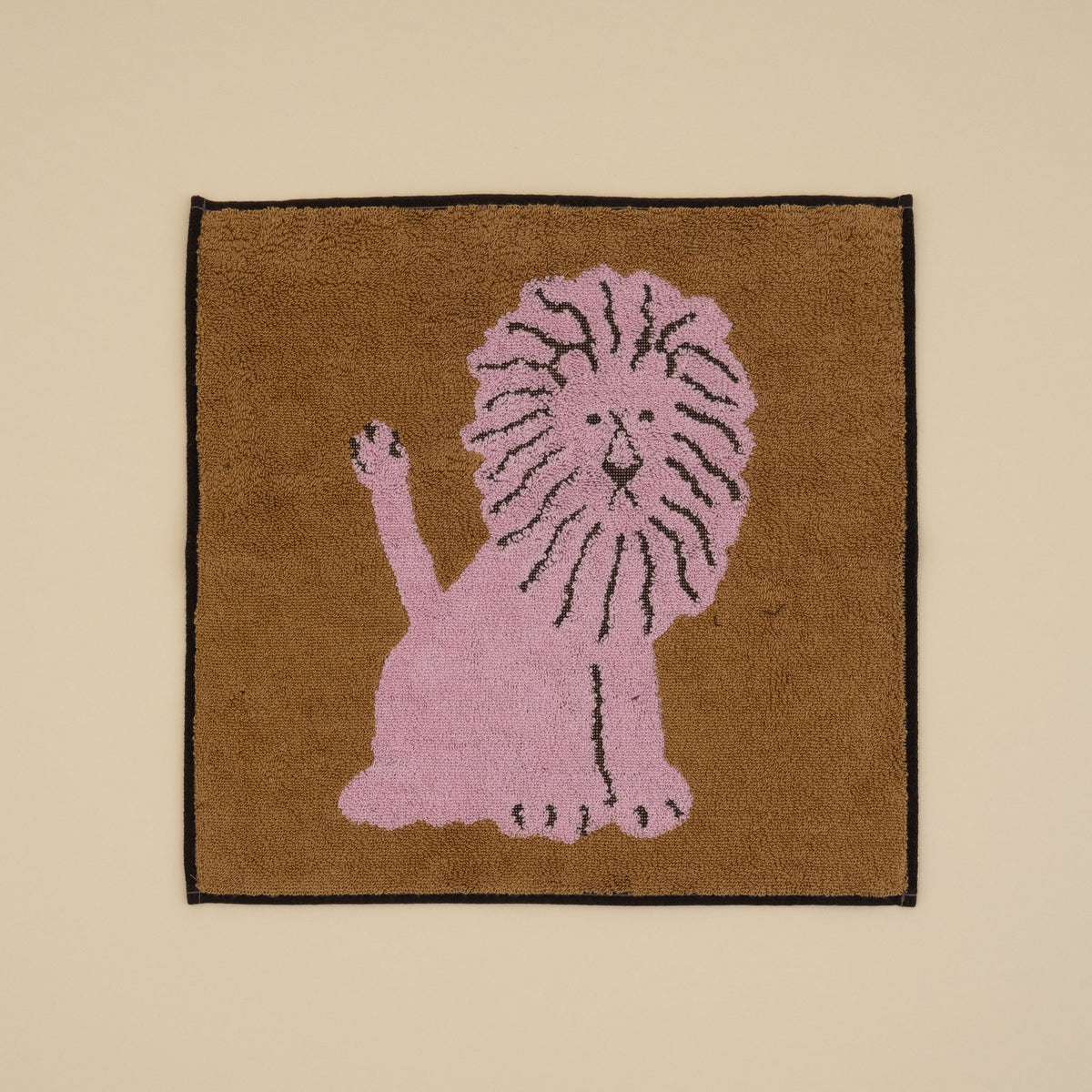 Warmgrey Tail terry face towel with an illustration of a pink lion on a brown ground